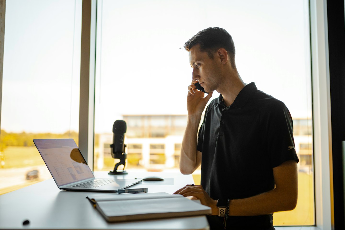 Man working on his laptop while talking on the phone.