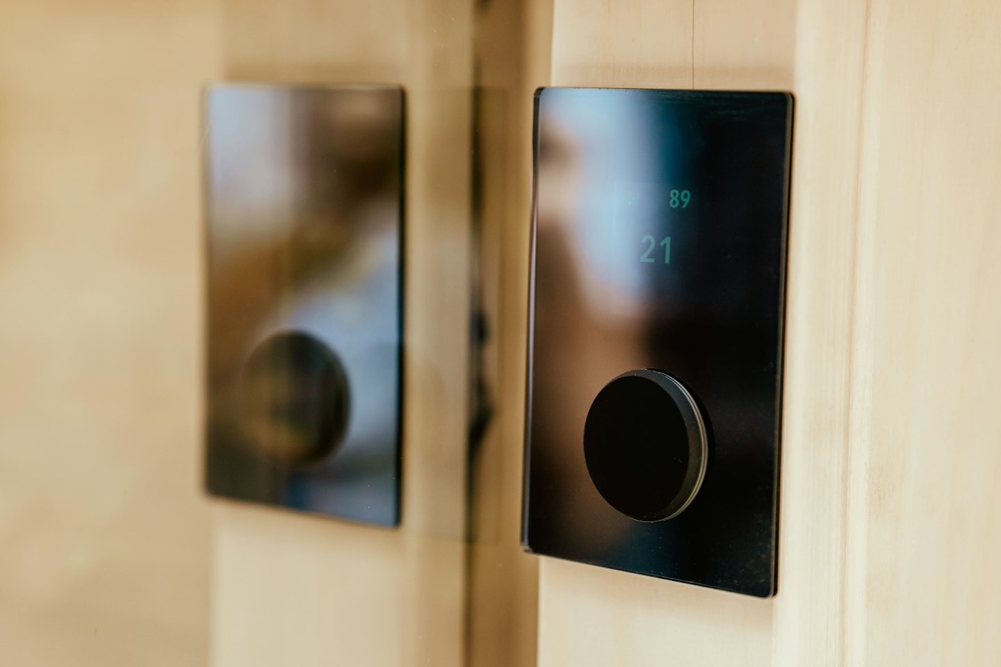 Two digital control panels with round knobs mounted on wood.